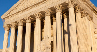 The facade of the United States Supreme Court building features tall columns, a sculpted pediment, and a statue at the entrance, illuminated by sunlight—an inspiring sight for lawyers in Chicago seeking justice.