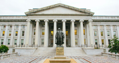 A large neoclassical building with tall columns, engraved "The Treasury Department," stands before a statue on a tiled plaza—reminiscent of the prestigious facades often seen at top corporate law offices and lawyers in Chicago.