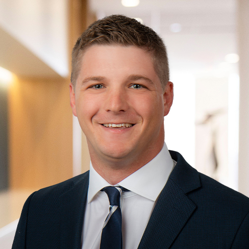 A man in a dark suit and tie smiles at the camera in a brightly lit corporate law office, reflecting the professionalism of lawyers in Chicago.