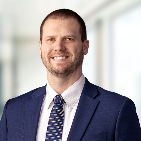 Man in a blue suit and polka dot tie smiling, standing in a brightly lit, professional indoor setting—perfectly representing the confidence and expertise of leading Chicago lawyers.