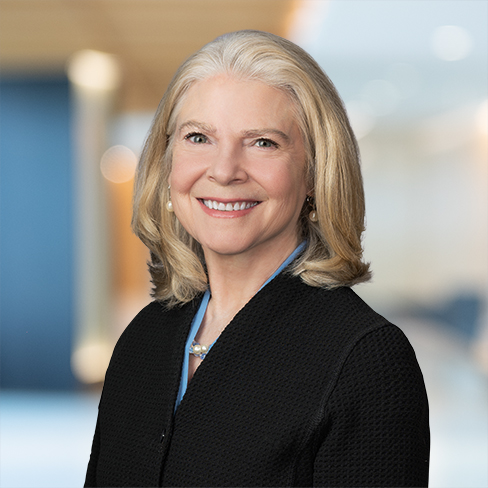 A woman with shoulder-length blonde hair, wearing a black blazer and pearl earrings, smiles at the camera in a professional indoor setting, representing leading chicago lawyers in intellectual property law.