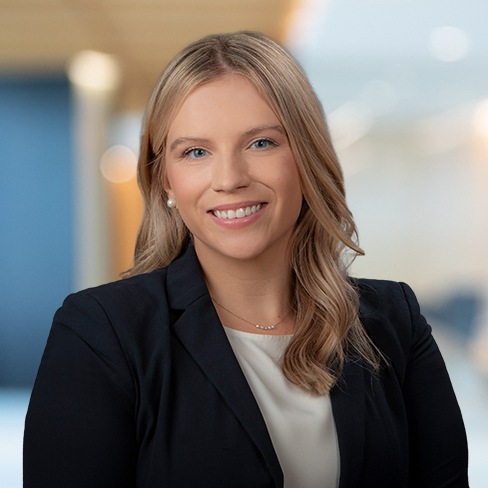 A woman with blonde hair wearing a black blazer and white top, smiling, posed in a modern law office setting—perfectly capturing the professionalism of Chicago lawyers.