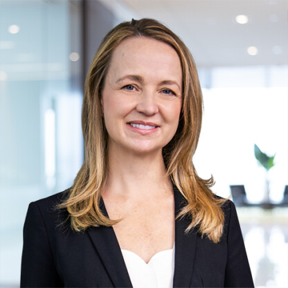A woman with long blonde hair wearing a black blazer and white top stands in a modern corporate law office, reflecting the professionalism of Chicago lawyers.