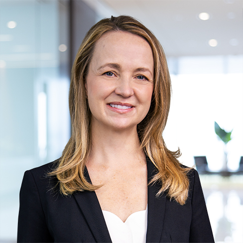 A woman with long blonde hair wearing a black blazer and white top stands in a modern corporate law office, reflecting the professionalism of Chicago lawyers.