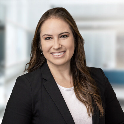 A woman with long brown hair wearing a black blazer and white top smiles in a modern law office, providing litigation support for lawyers in Chicago.