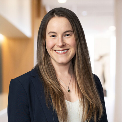 A woman with long straight brown hair, wearing a navy blazer and white top, smiles at the camera in a brightly lit indoor setting—reflecting the professionalism of top Chicago lawyers.