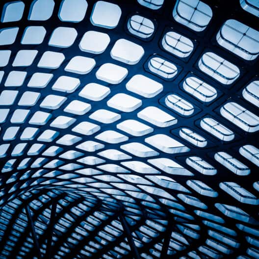 Curved architectural ceiling structure with a grid pattern of square openings, viewed from below at a corporate law office, letting light filter through.