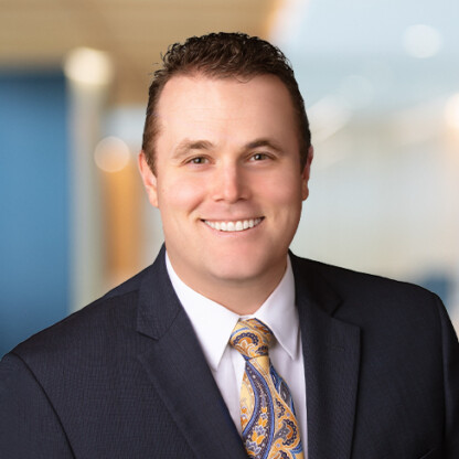 A man in a dark suit, white shirt, and patterned tie smiles at the camera in a professional indoor setting, representing top litigation support provided by experienced Chicago lawyers.