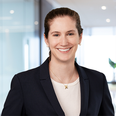 A woman in a dark blazer and white top smiles in a modern law office with glass walls and natural light, reflecting the professional atmosphere of Chicago lawyers.