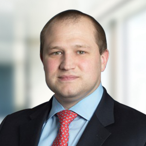 A man in a suit and red tie is posing for a professional headshot against a blurred office background, reflecting the polished image of professionals at leading Chicago law offices.