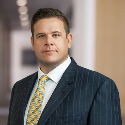 A man in a pinstripe suit and yellow striped tie stands in a blurred office hallway, looking directly at the camera with a neutral expression—reflecting the professional demeanor of top lawyers in Chicago.