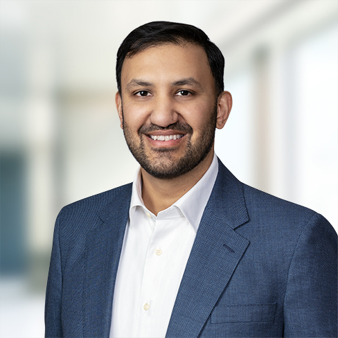 A man with short dark hair and a beard wearing a blue suit jacket and white shirt, standing in front of a blurred indoor background, representing chicago lawyers specializing in intellectual property law.