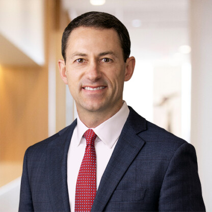 Man in a dark suit and red tie smiles at the camera in a bright, modern office setting, reflecting the professionalism of top Chicago lawyers.