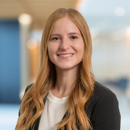 A woman with long blonde hair, wearing a black blazer and white top, smiles at the camera in a brightly lit law office, reflecting the professionalism of Chicago lawyers.
