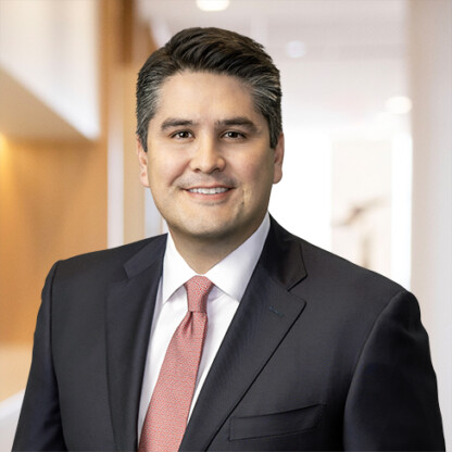 A man in a dark suit and red tie stands smiling in a brightly lit, modern corporate law office hallway, reflecting the professionalism of top lawyers in Chicago.