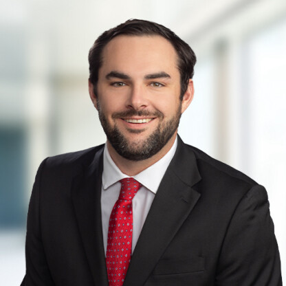 A man in a black suit, white shirt, and red tie smiles at the camera against a blurred indoor background, reflecting the professional image often seen at top Chicago law offices.
