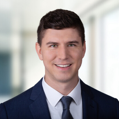A man in a navy suit, white shirt, and patterned tie—representative of top lawyers in Chicago—smiles at the camera in a bright, blurred office setting.