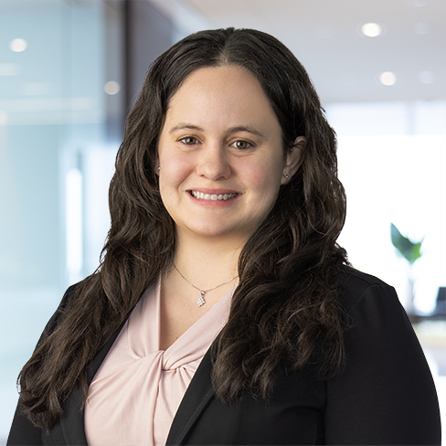A woman with long dark hair, wearing a light pink blouse and black blazer, smiles in an office setting—reflecting the professionalism of top lawyers in Chicago.