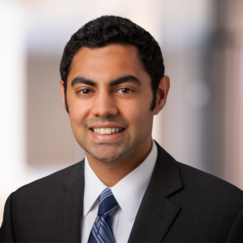 A man in a dark suit and striped tie smiles at the camera against a blurred indoor background, reflecting the professionalism often found in Chicago lawyers and leading law offices.