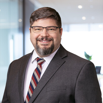 A man in a suit and tie stands confidently, embodying the professionalism found in a corporate law office.
