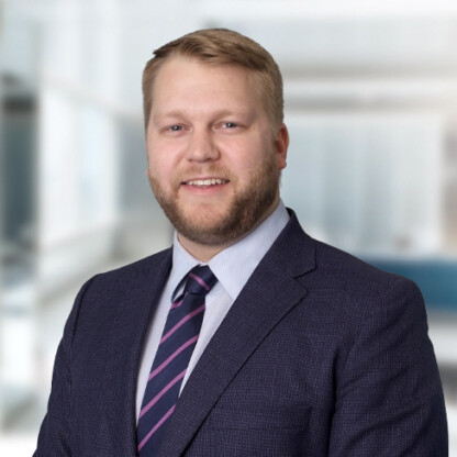 A man in a suit and striped tie smiles at the camera in a modern law office, reflecting the professionalism of top lawyers in Chicago.