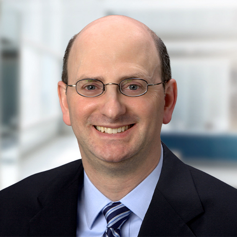 Man with glasses, balding head, and wearing a suit and tie, smiling at the camera in a modern corporate law office, representing top lawyers in Chicago.