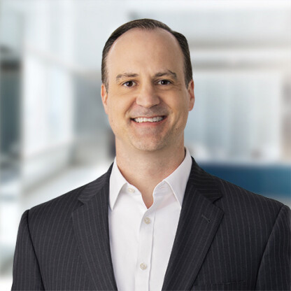 Man in a dark pinstripe suit and white shirt, smiling, stands in a modern, bright corporate law office—an environment typical of top Chicago lawyers.