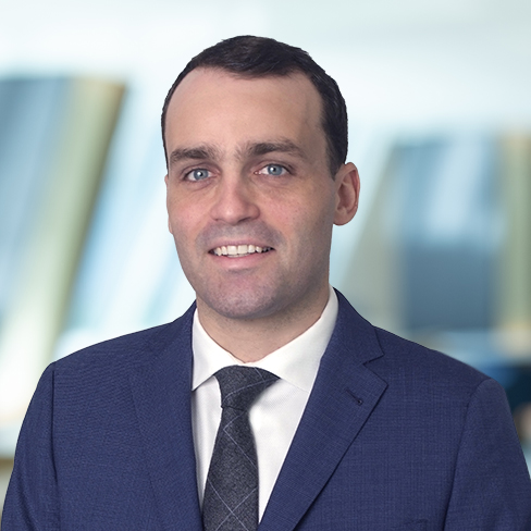A man in a navy blue suit, white shirt, and patterned tie poses in front of a blurred corporate law office, embodying the professionalism of top Chicago lawyers.