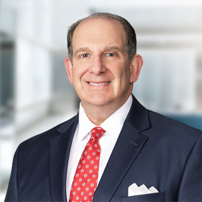 A middle-aged man in a navy suit, white shirt, and red patterned tie stands indoors, smiling at the camera, reflecting the professionalism often seen in Chicago lawyers at a top corporate law office.