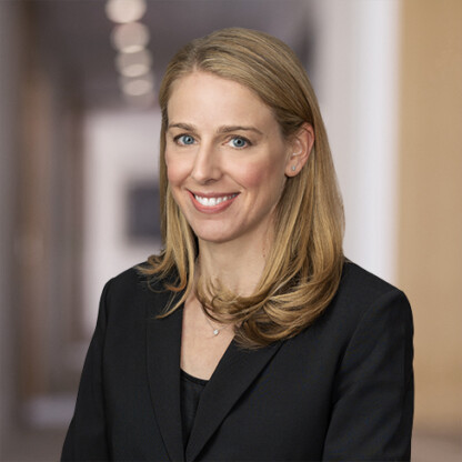 A woman with long blonde hair, wearing a black blazer, smiles at the camera in a professional indoor setting at one of the leading law offices offering litigation support for lawyers in Chicago.