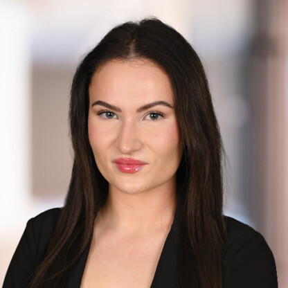 A woman with long dark hair wearing a black top poses for a professional headshot against a blurred background, representing the professionalism found in Chicago lawyers and law offices.