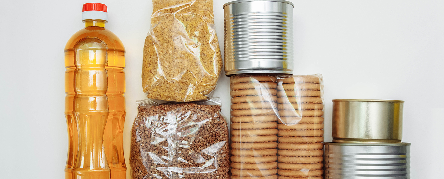 Assorted non-perishable food items, perfect for Chicago lawyers or law offices needing convenient snacks—includes a bottle of cooking oil, two types of grains in plastic bags, round biscuits in plastic, and three tin cans.