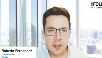 A man with glasses speaks during a video call; the background shows large windows and a blurred cityscape. Text overlay reads: "Roberto Fernandez, Senior Counsel, Chicago – Foley & Lardner LLP," highlighting expertise among Chicago lawyers.