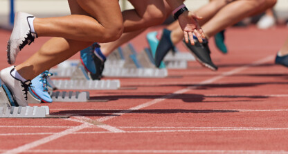 Sprinters in athletic gear launch from starting blocks on a red track, captured in mid-motion at the beginning of a race—much like Chicago lawyers springing into action to provide top-notch litigation support.