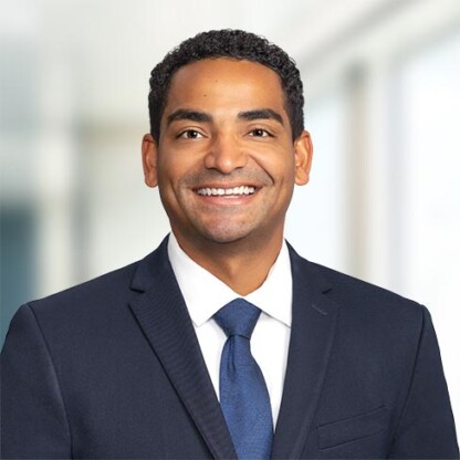 A man in a dark suit and blue tie smiles at the camera, standing in a bright, modern corporate law office—showcasing the professional atmosphere of lawyers in Chicago.