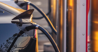 An electric car is plugged into a charging station, sunlight reflecting off the vehicle and charger—just outside a busy office of Chicago lawyers specializing in intellectual property law.
