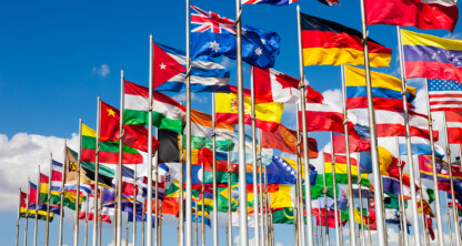 A group of international flags from various countries are displayed on flagpoles against a blue sky with scattered clouds, symbolizing global connections often navigated by lawyers in Chicago and experts in intellectual property law.