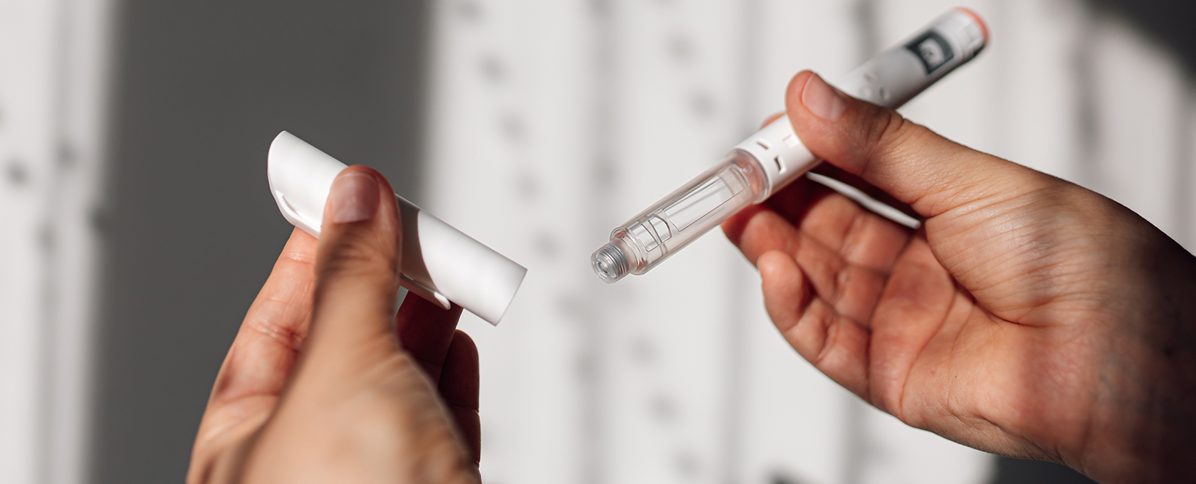 A person holds an insulin pen in one hand and removes the cap with the other hand, illustrating precision and care much like chicago lawyers handle complex litigation support.