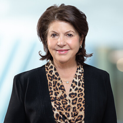 A woman with short, dark hair wearing a black blazer and a leopard print blouse, smiling at the camera against a blurred light background—perfectly embodying the professionalism of top Chicago lawyers.