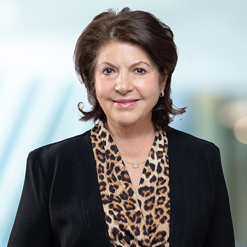 A woman with short, dark hair wearing a black blazer and a leopard print blouse, smiling at the camera against a blurred light background—perfectly embodying the professionalism of top Chicago lawyers.