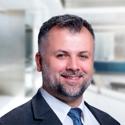 A man in a suit and tie smiles at the camera in a modern office setting, representing experienced lawyers in Chicago who specialize in intellectual property law.