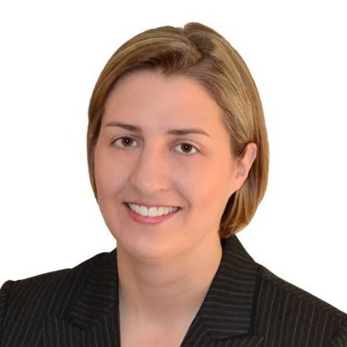 A person with short light brown hair, wearing a dark pinstripe blazer, is smiling against a plain white background—reflecting the professionalism found at top corporate law offices.